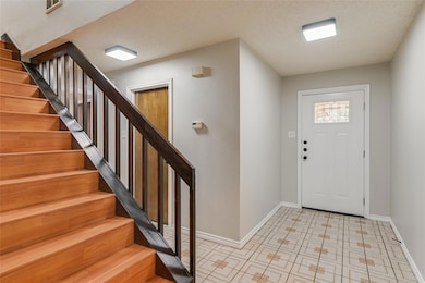 Foyer entrance featuring stairs, a textured ceili