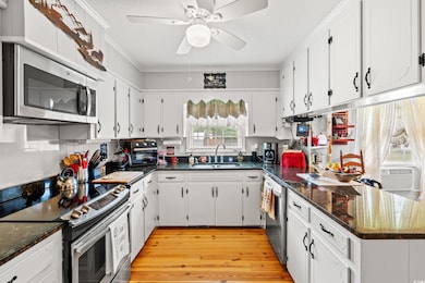 Kitchen featuring appliances with stainless steel finishes, crown molding, white cabinets, a textured ceiling, and ceiling fan