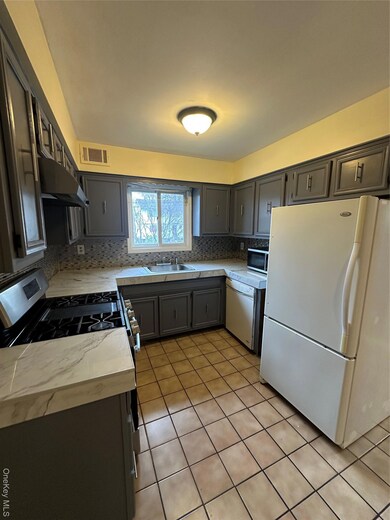 Kitchen with gray cabinets, fridge, light tile patterned floors, range, and dishwashing machine