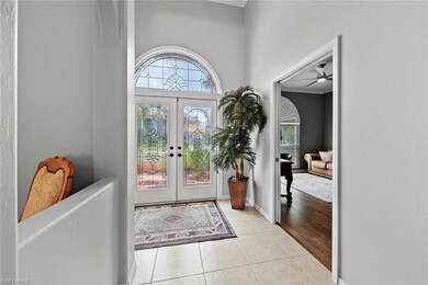 Entrance foyer featuring a towering ceiling, light tile flooring, ceiling fan, ornamental molding, and french doors