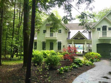 Paved driveway flanked by a stonewall and boxwoods