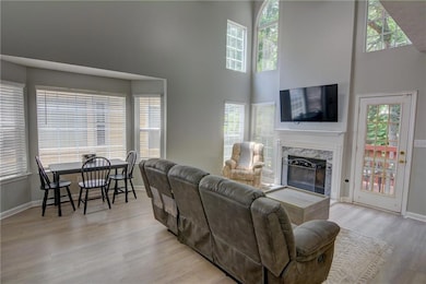 Living area with a towering ceiling, wood finished floors, a high end fireplace, and baseboards