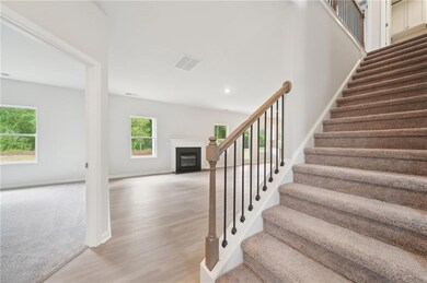 Staircase featuring wood finished floors, a glass covered fireplace, and carpet