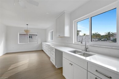 Kitchen with a sink, light wood finished floors, light countertops, white cabinets, and a ceiling fan