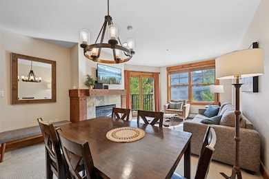 Carpeted dining area featuring a chandelier and a fireplace