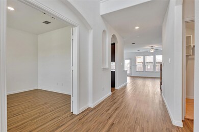 Hall featuring arched walkways, wood finished flo