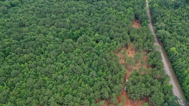 Aerial view of property and surrounding area featuring a heavily wooded area and property parcel outlined