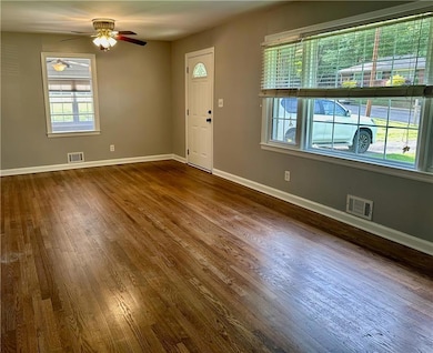 Foyer entrance with dark wood-style floors, ceiling fan, and baseboards