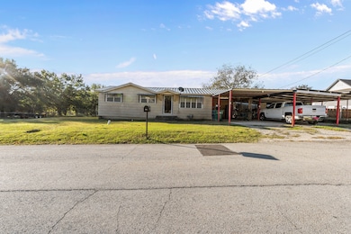 Ranch-style house with a front yard, an attached carport, driveway, and a metal roof