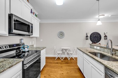 Kitchen featuring appliances with stainless steel finishes, a sink, crown molding, light wood-style flooring, and white cabinets