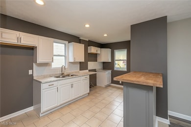 Kitchen with butcher block countertops, white cabinetry, decorative backsplash, light tile patterned flooring, and recessed lighting