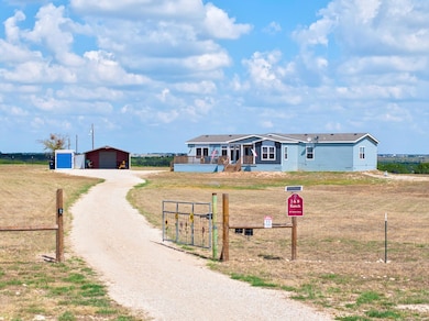 View of front of house with an outbuilding, dirt 