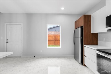Kitchen featuring white cabinetry, stainless steel fridge, decorative backsplash, and range with electric cooktop