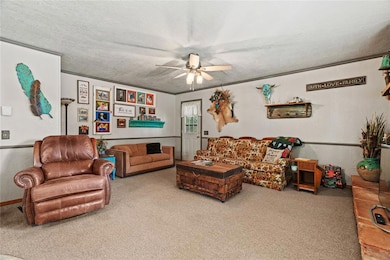 Carpeted living area with a textured ceiling and ceiling fan