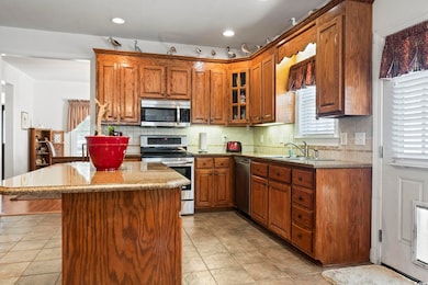 Kitchen featuring appliances with stainless steel finishes, light stone countertops, healthy amount of natural light, recessed lighting, and crown molding