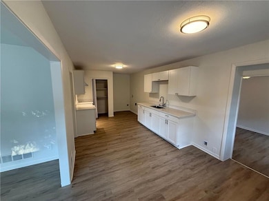 Kitchen with white cabinets, light countertops, dark wood-style floors, and a textured ceiling