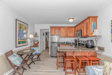 Kitchen with crown molding, a peninsula, light woo