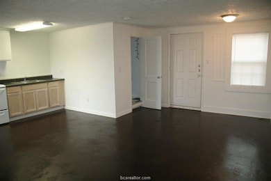 Kitchen with a sink, baseboards, a textured ceilin