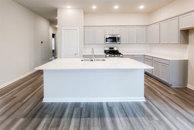Island kitchen has built-in stainless appliances, lots of cabinet space, trendy backsplash and large breakfast bar