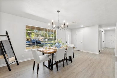 Dining room with light wood finished floors, a chandelier, and recessed lighting