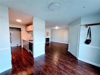 Kitchen with dark wood finished floors, tasteful backsplash, open floor plan, a fireplace, and black dishwasher