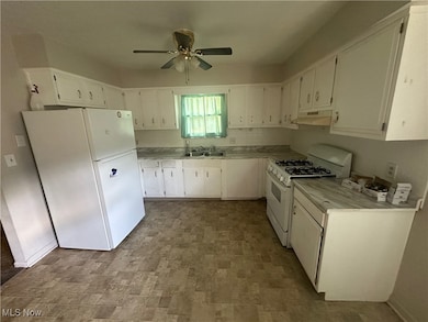 Kitchen with light countertops, white appliances, white cabinetry, a ceiling fan, and under cabinet range hood