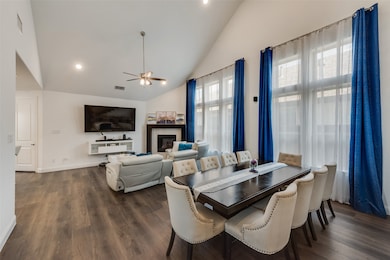 Dining area with a glass covered fireplace, high vaulted ceiling, recessed lighting, dark wood-style flooring, and a ceiling fan