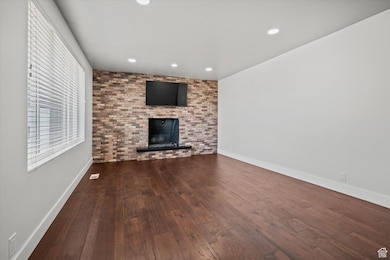 Unfurnished living room with wood-type flooring, recessed lighting, and a brick fireplace