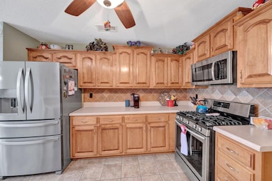 Kitchen with appliances with stainless steel finishes, light countertops, tasteful backsplash, light tile patterned floors, and a textured ceiling. Fridge is negotiable.