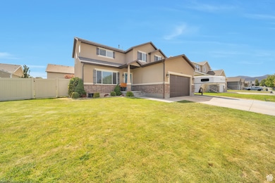 View of front facade featuring stucco siding, an attached garage, driveway, and brick siding