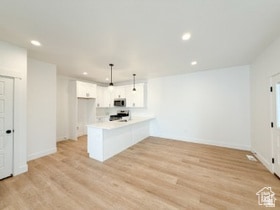 Kitchen featuring light countertops, a peninsula, recessed lighting, white cabinets, and light wood finished floors
