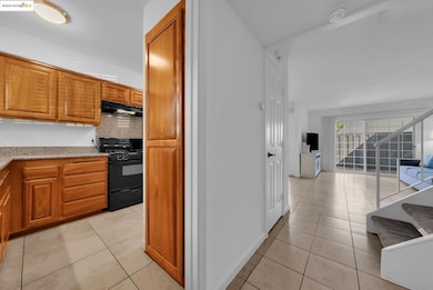 Kitchen with light tile patterned floors, brown cabinets, and black gas range