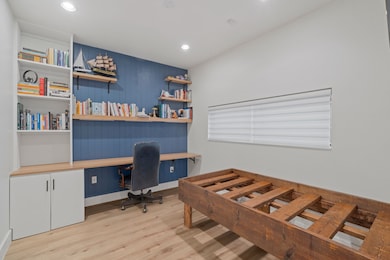Office with built in desk and light hardwood / wood-style floors
