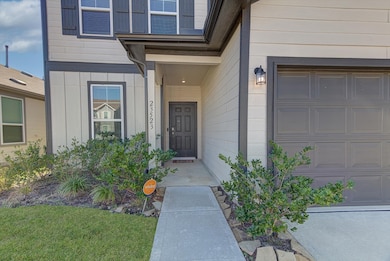 Charming entryway with a covered porch, modern exterior, and neatly landscaped front yard. The garage door is adjacent, and there is a welcoming front door with sleek lighting.