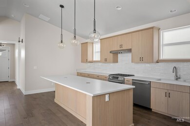 Kitchen with light brown cabinets, a barn door, dark wood finished floors, a center island, and lofted ceiling
