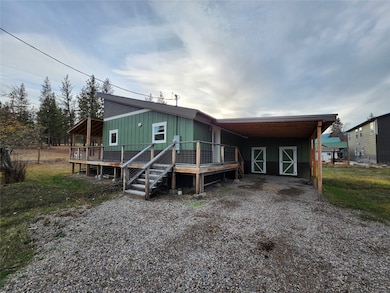 View of front of house featuring board and batten siding, a carport, a wooden deck, and driveway