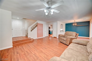 Living room featuring light wood-style floors, stairs, and a ceiling fan