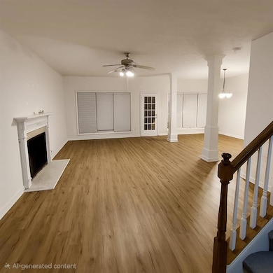 Unfurnished living room with light wood finished floors, decorative columns, a fireplace, ceiling fan, and stairway