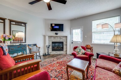 Living room with a textured ceiling, ceiling fan, a fireplace, and wood-type flooring