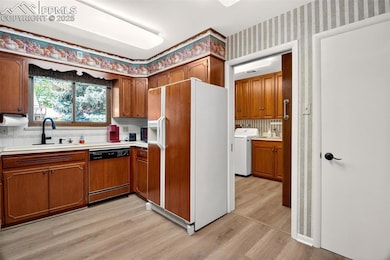 Kitchen with white refrigerator with ice dispenser, light wood-style floors, dishwasher, brown cabinetry, and wallpapered walls
