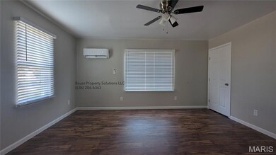Unfurnished room featuring dark wood-style floors, an AC wall unit, and ceiling fan