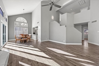 Living area with high vaulted ceiling, dark wood finished floors, ceiling fan, a chandelier, and healthy amount of natural light