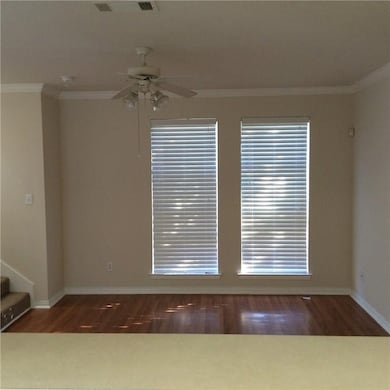 Empty room featuring crown molding, dark wood-style floors, stairs, and a ceiling fan