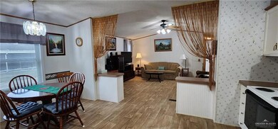 Dining room with ornamental molding, ceiling fan with notable chandelier, a textured ceiling, light hardwood / wood-style flooring, and lofted ceiling