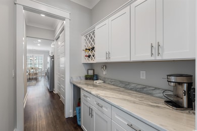 Kitchen featuring freestanding refrigerator, dark wood-type flooring, white cabinetry, light stone countertops, and recessed lighting