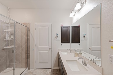 Bathroom featuring double vanity, a textured wall, and a shower stall