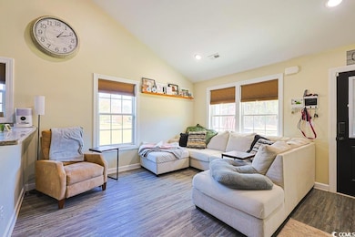 Living room with healthy amount of natural light, wood finished floors, recessed lighting, and high vaulted ceiling