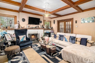 Living area with coffered ceiling, beamed ceiling, a brick fireplace, and french doors