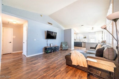 Living room with wood finished floors, vaulted cei