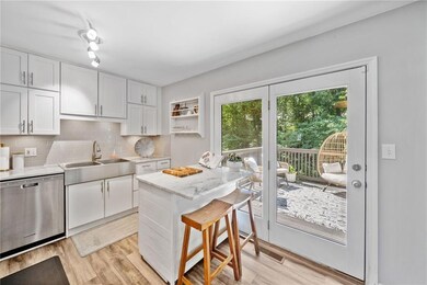 Kitchen with appliances with stainless steel finishes, stone countertops, tasteful backsplash, white cabinetry, upgraded dishwasher, and wood-style floors.